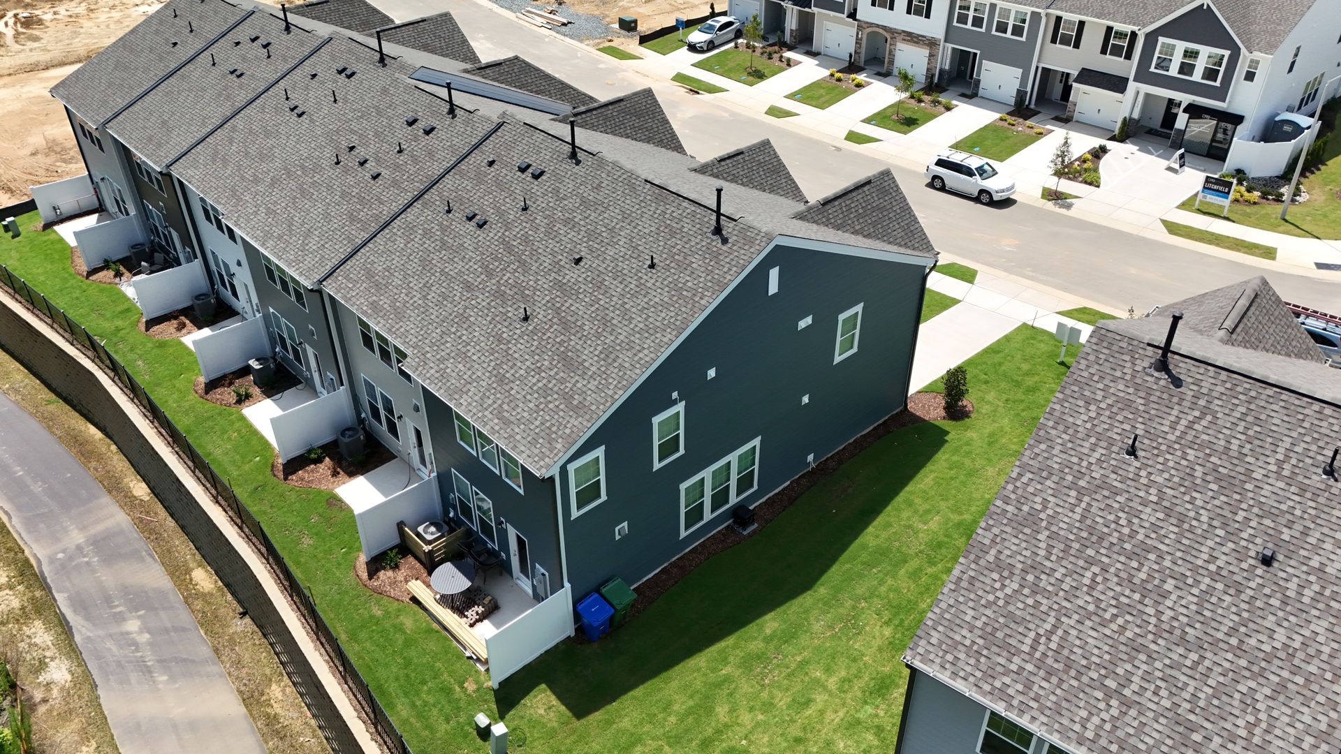 Row of townhouses with dark gray siding and green lawns.