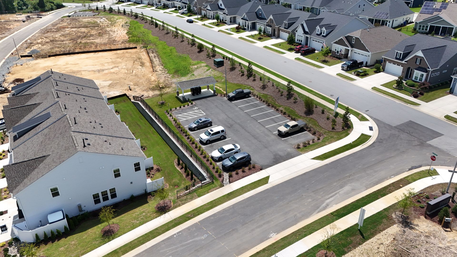 Aerial view of new residential development with houses, streets, parking, and a construction site.