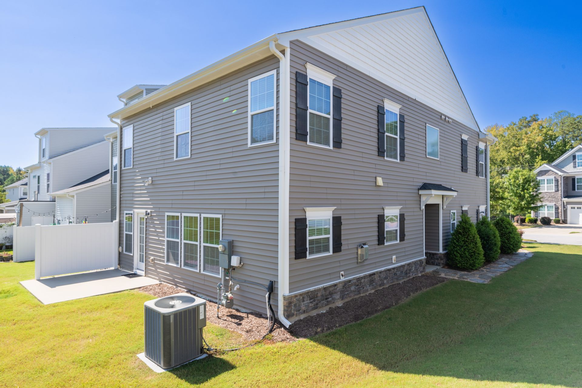 Gray two-story house with black shutters, on a grassy lawn. Air conditioning unit visible.