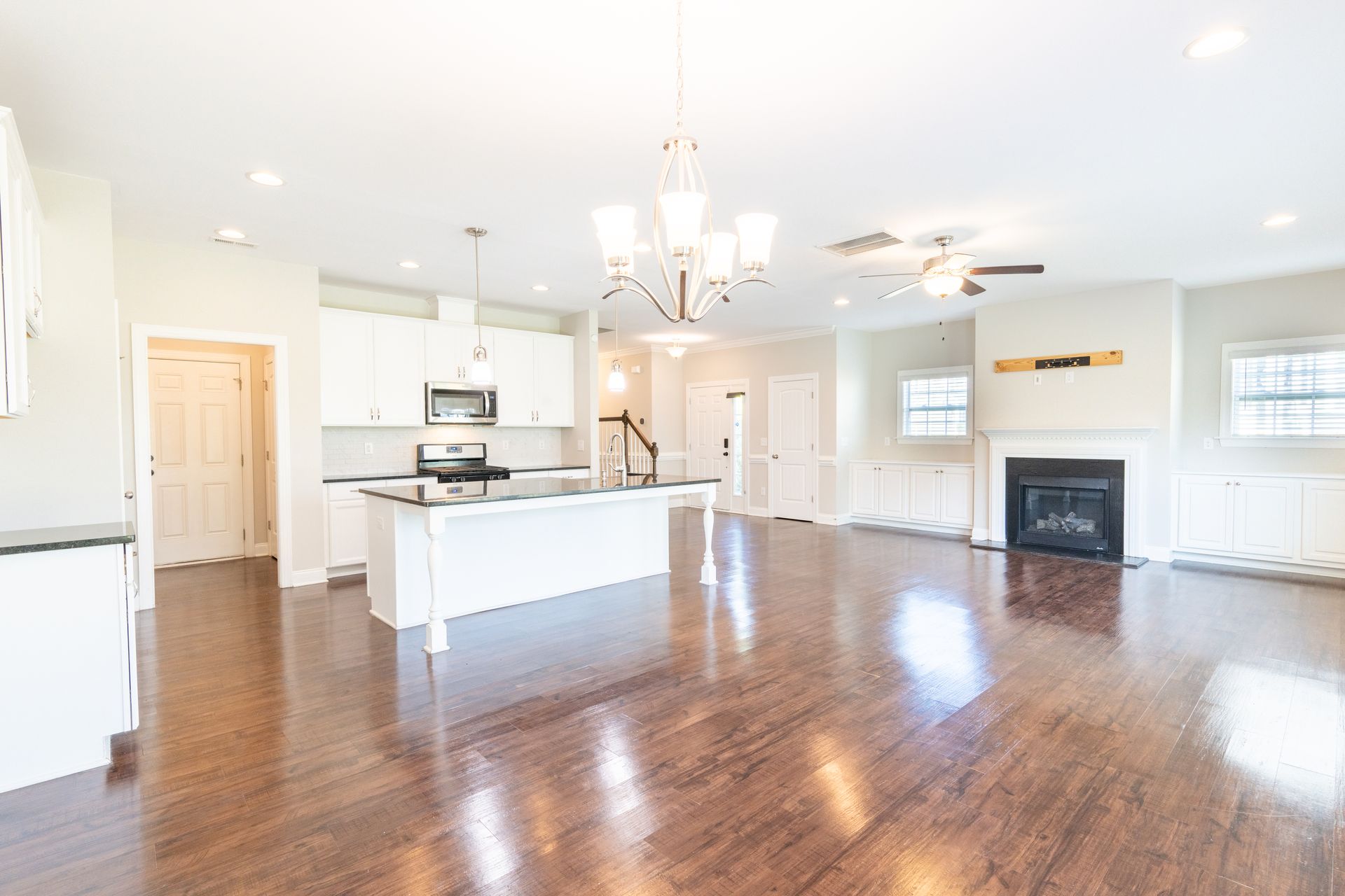 Open-concept kitchen and living area with white cabinets, dark floors, and fireplace.