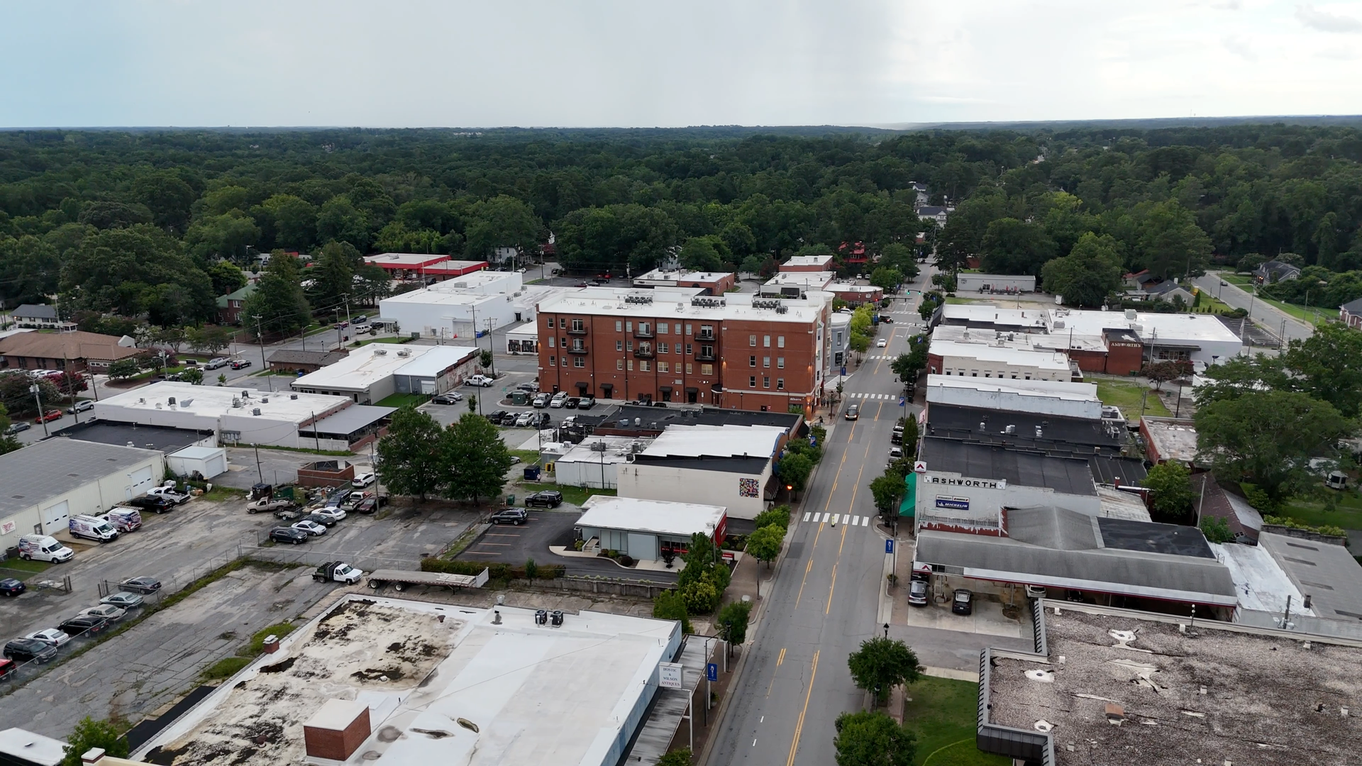 Aerial view of a small town with a brick building in the center, surrounded by trees and other buildings.