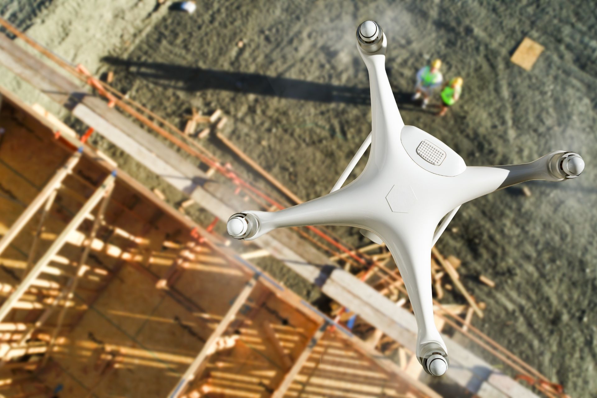 Drone hovering over a construction site, capturing an aerial view of the wooden framework and workers.