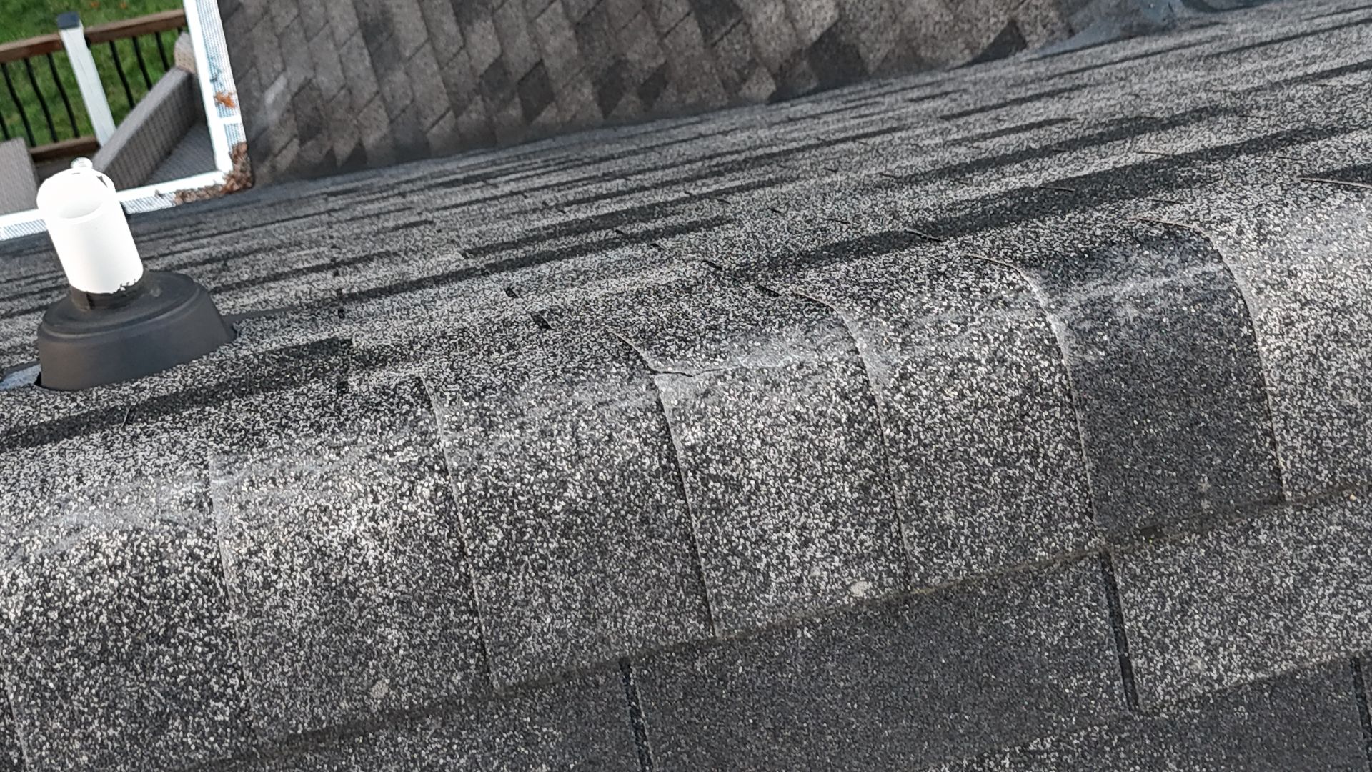 Close-up of weathered asphalt shingles on a roof, with visible granule loss.