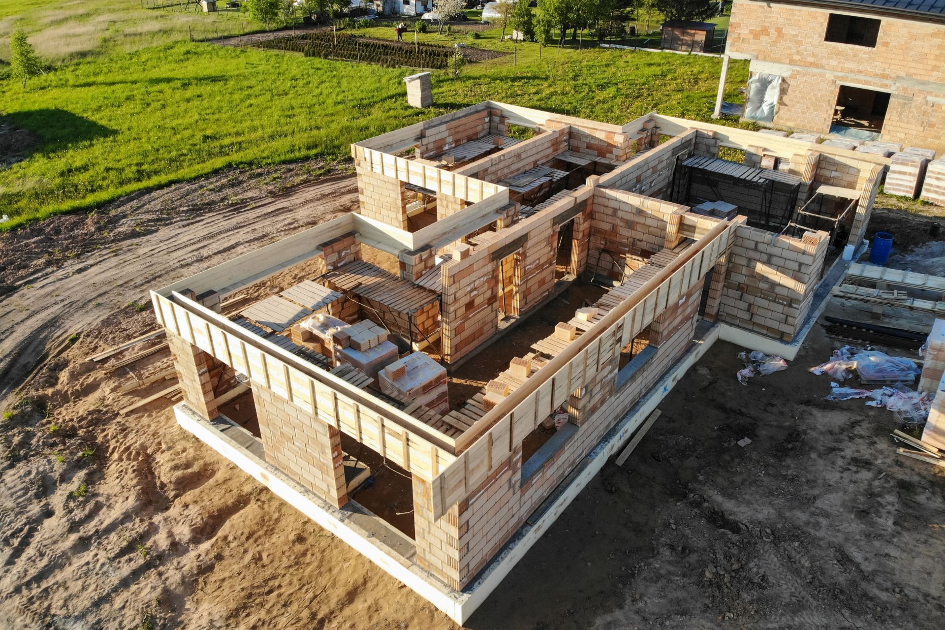Construction site aerial view of a brick house framework. The house has unfinished walls and sits on a foundation.