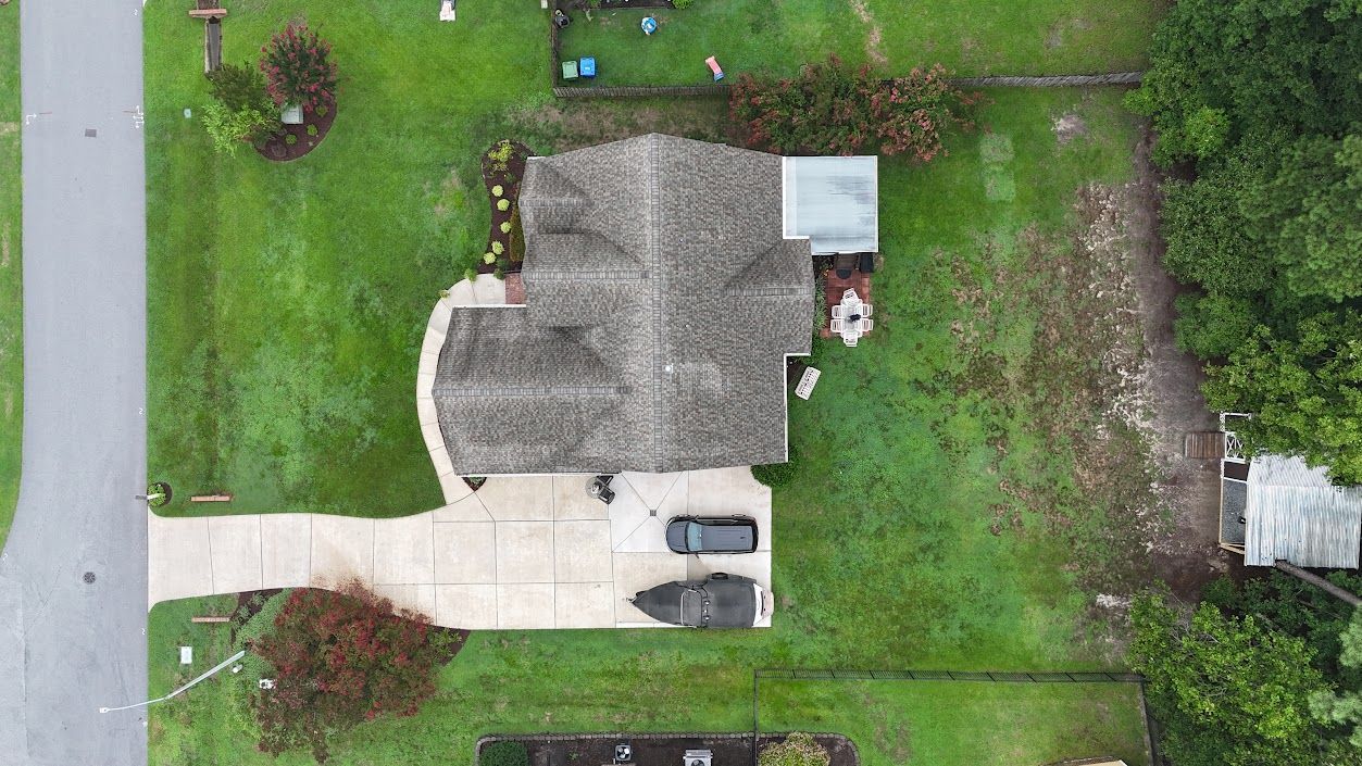 Overhead view of a house with a driveway and green lawn; a car parked in the driveway.