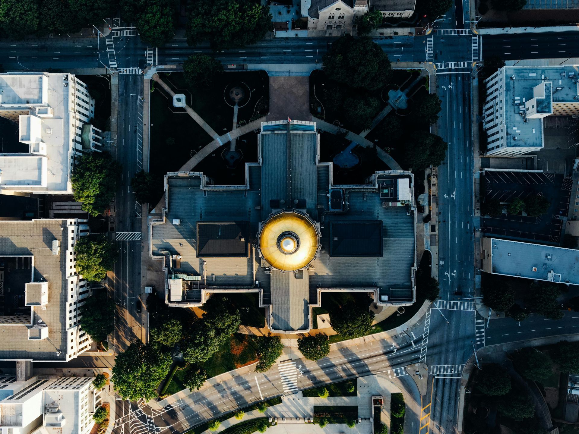 Aerial view of a government building with a golden dome, surrounded by roads and other buildings in a city.