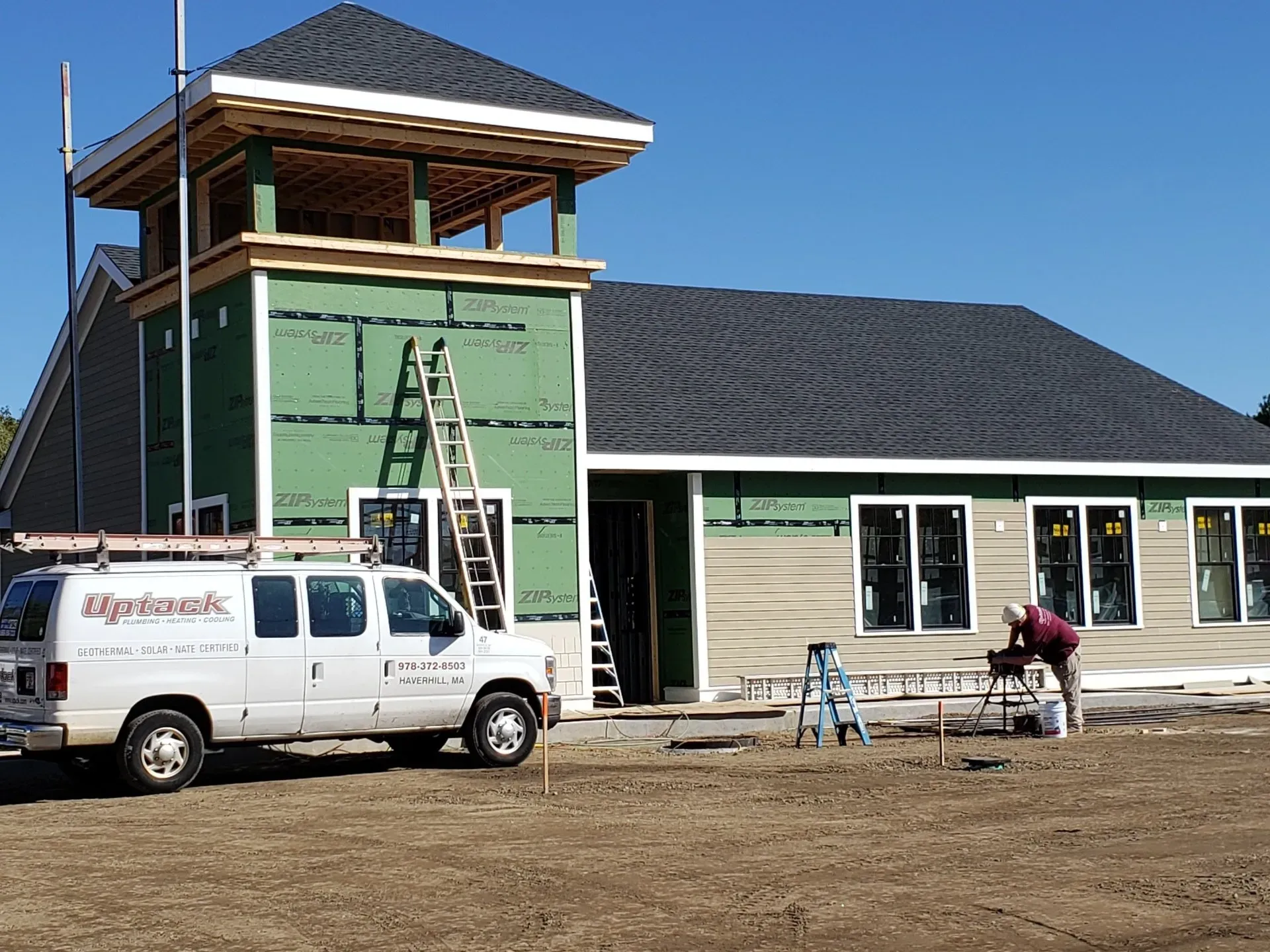 A white van is parked in front of a house under construction