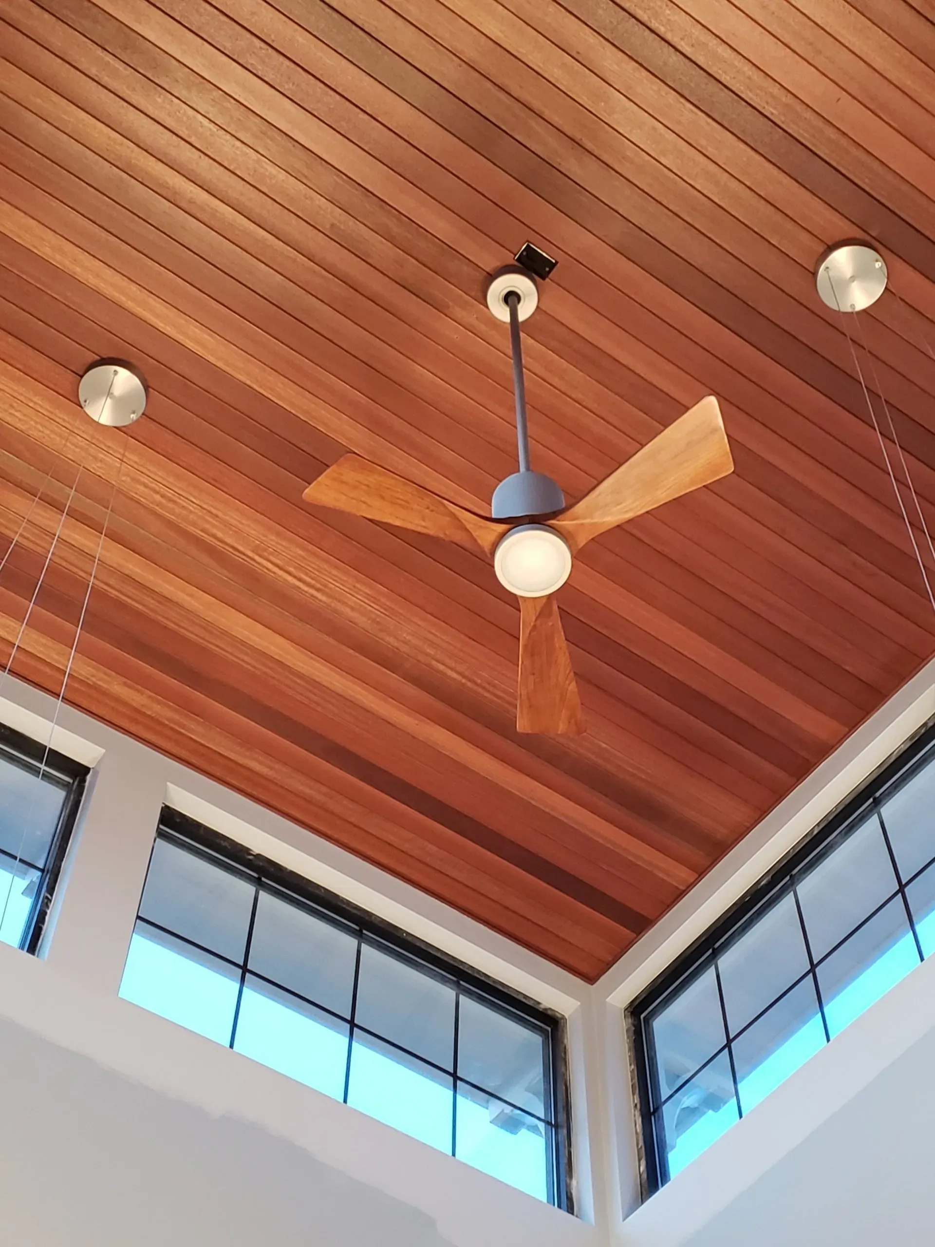 A ceiling fan is hanging from the ceiling in a room with lots of windows