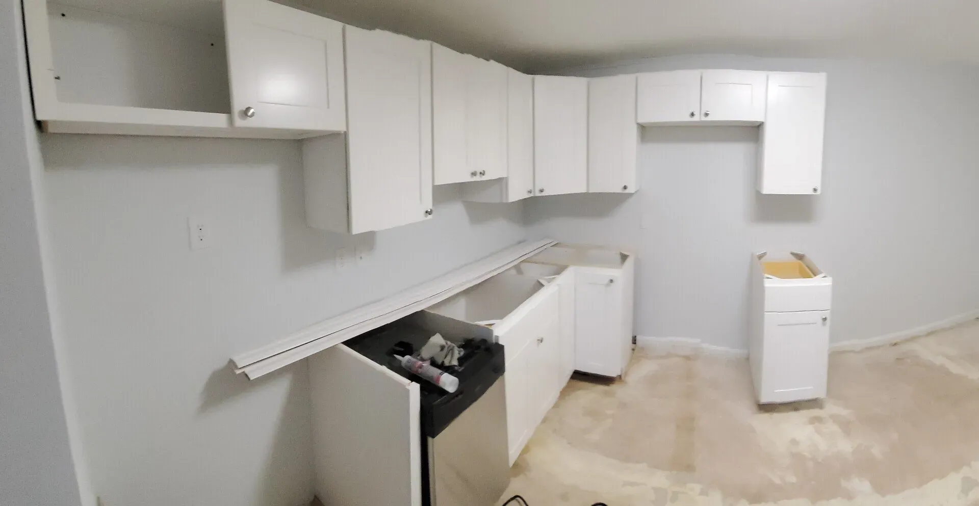 A kitchen with white cabinets and a stainless steel dishwasher