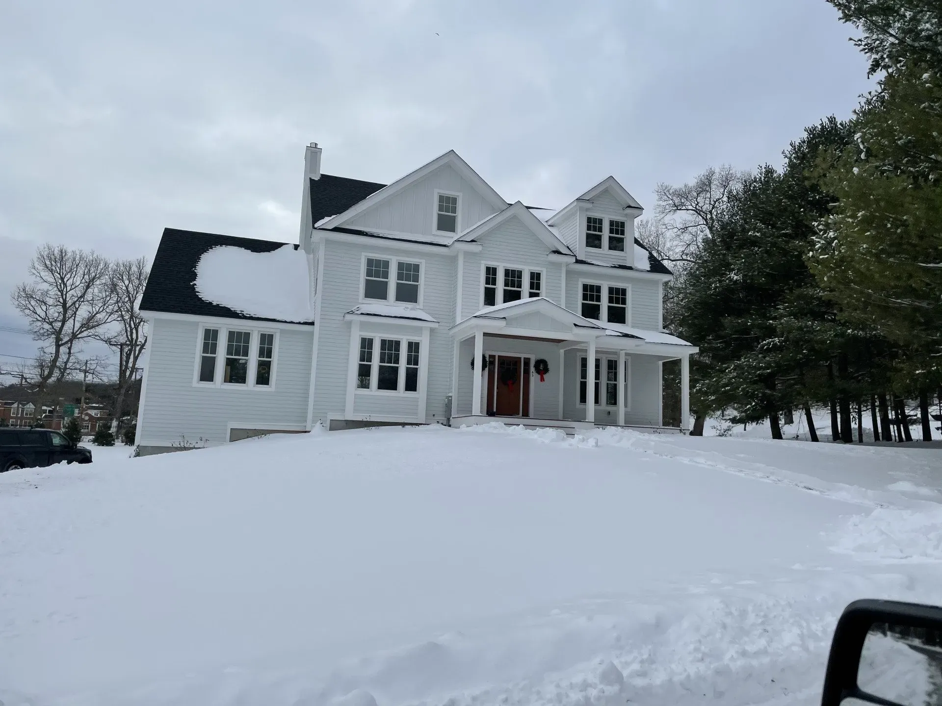 A large white house is covered in snow.