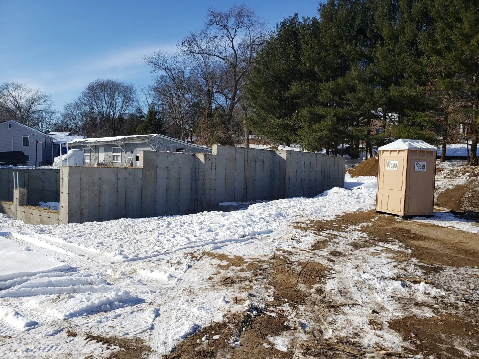 A concrete wall is being built in the snow next to a wooden box.