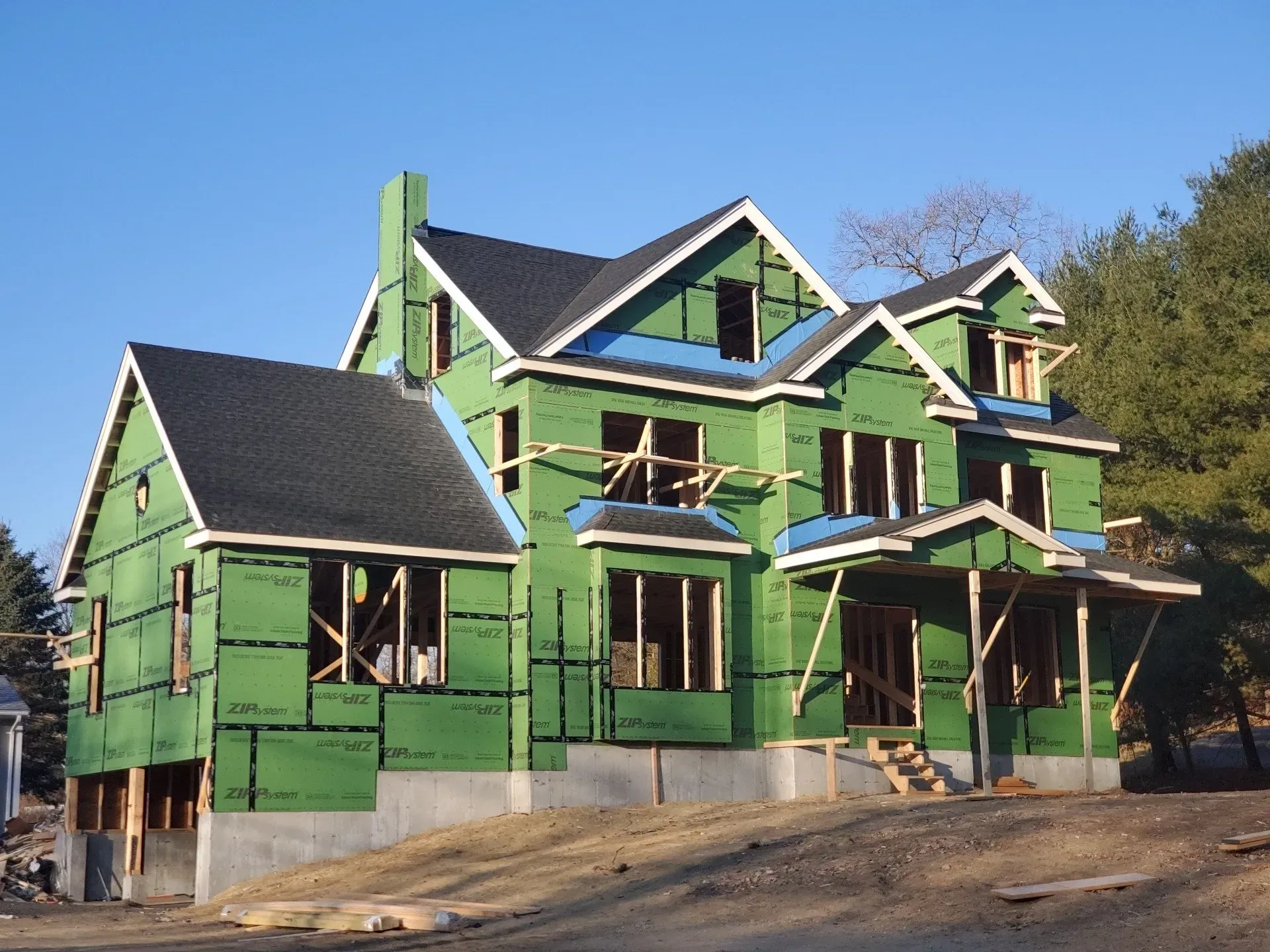 A large house is being built with green siding