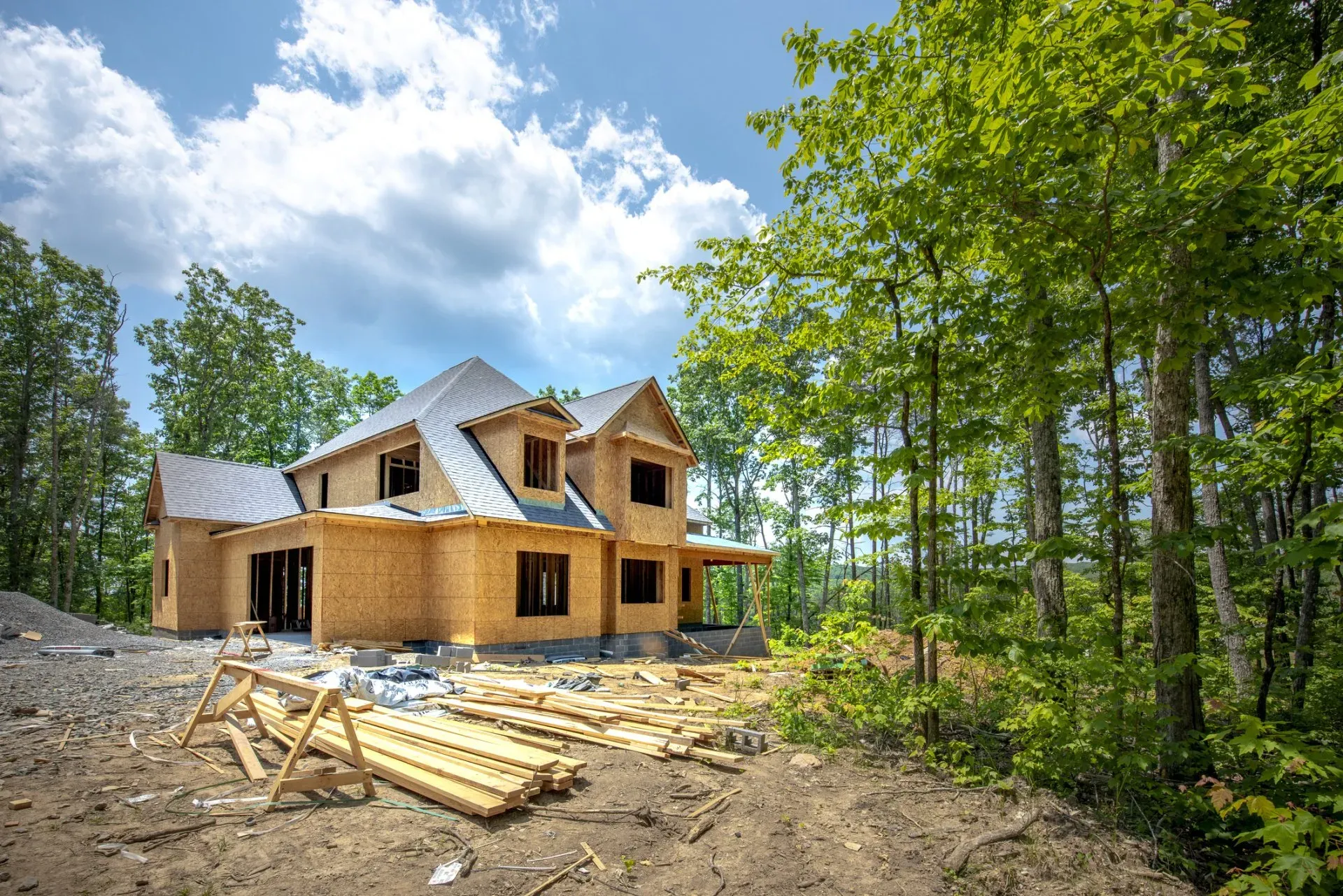 A large wooden house is being built in the middle of a forest.