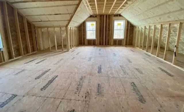 A room with a wooden floor and a ceiling in a house under construction.