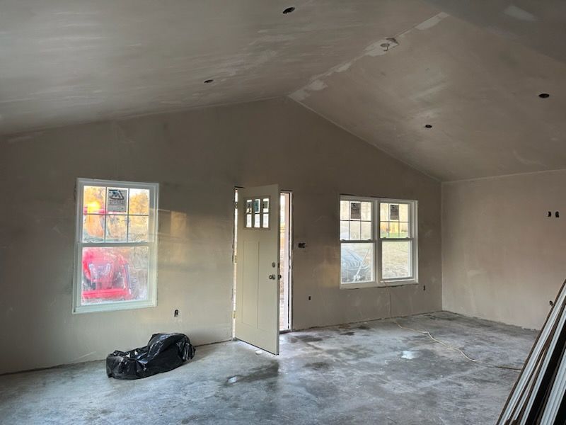 A large empty room with a vaulted ceiling and two windows.
