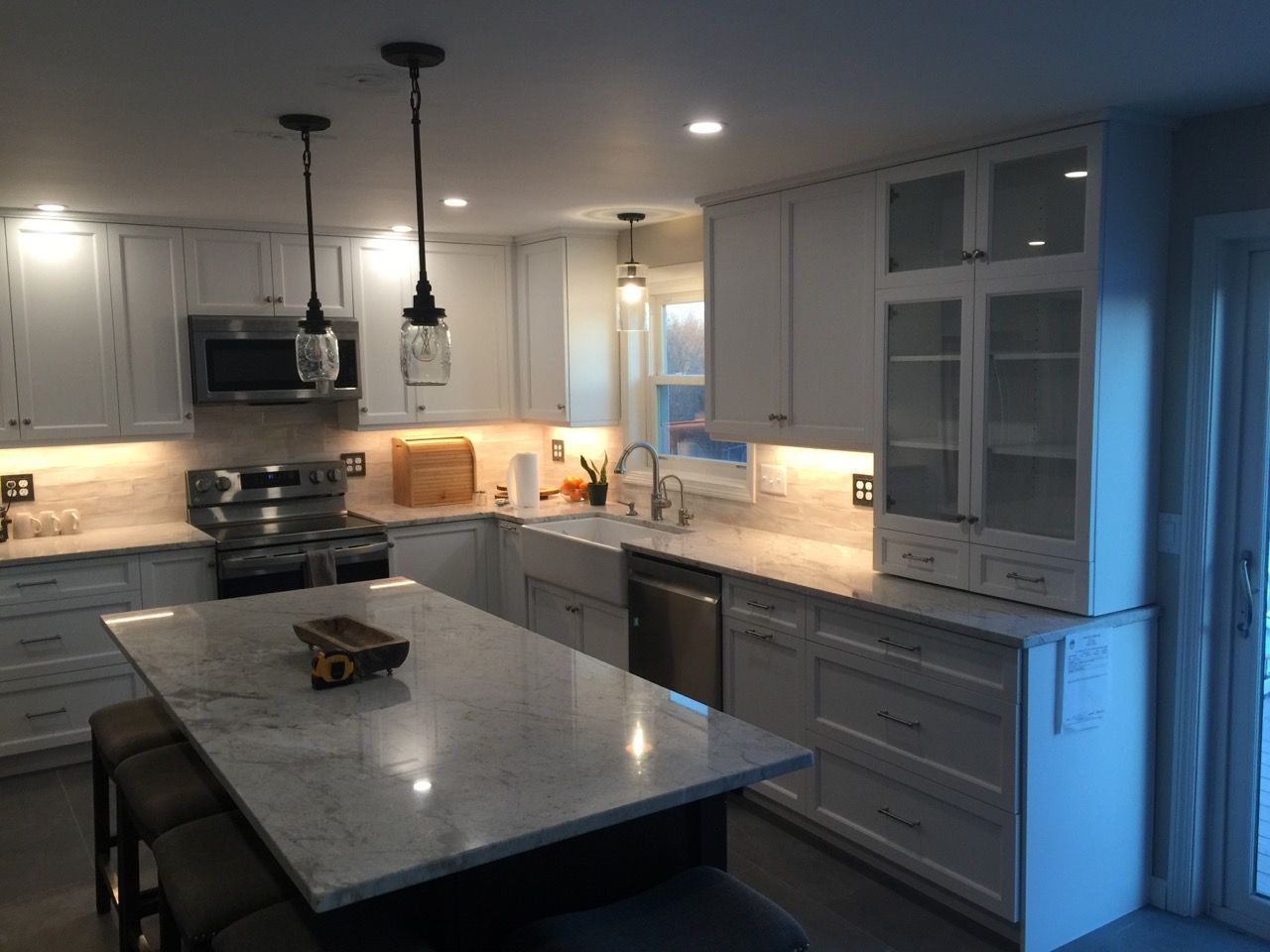 A kitchen with white cabinets and a marble counter top
