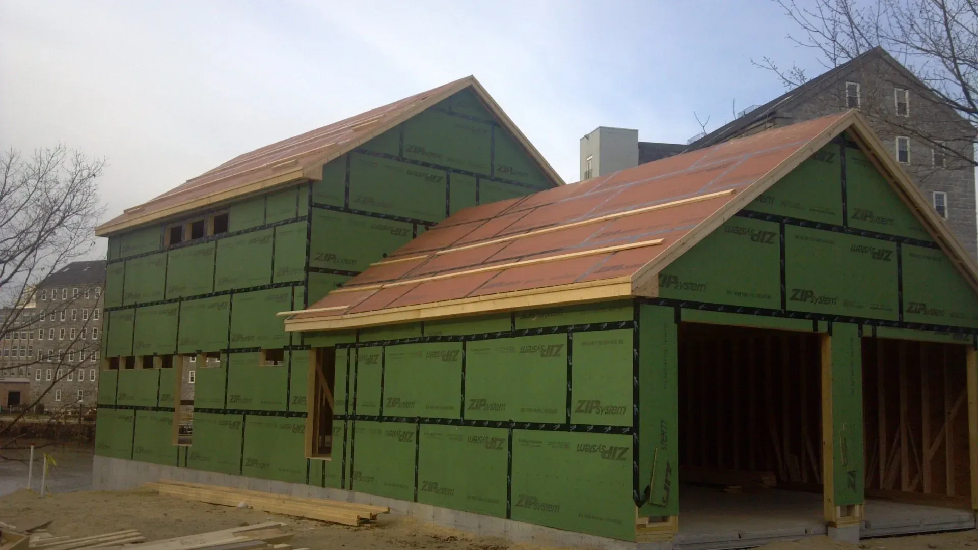 A house is being built with green siding and a red roof.