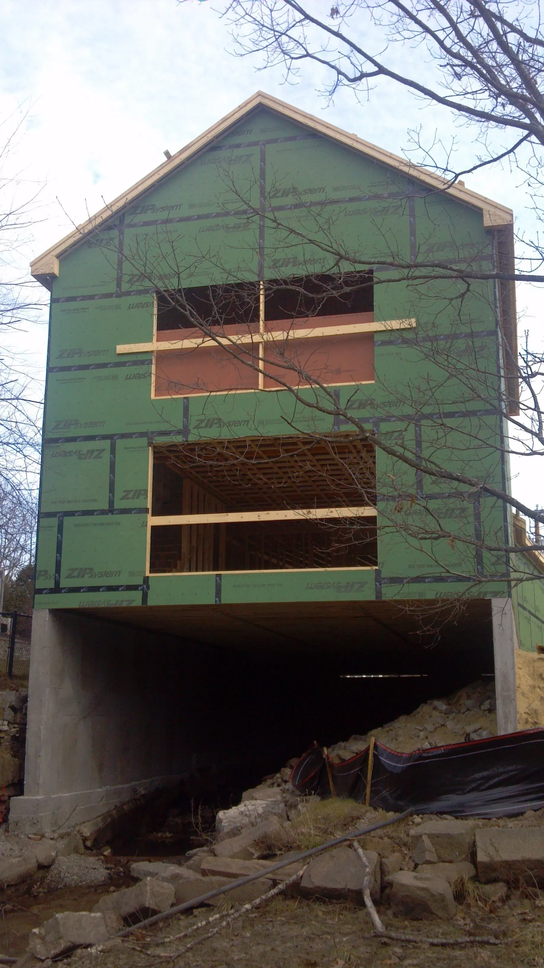 A house is being built with green siding and a wooden roof.