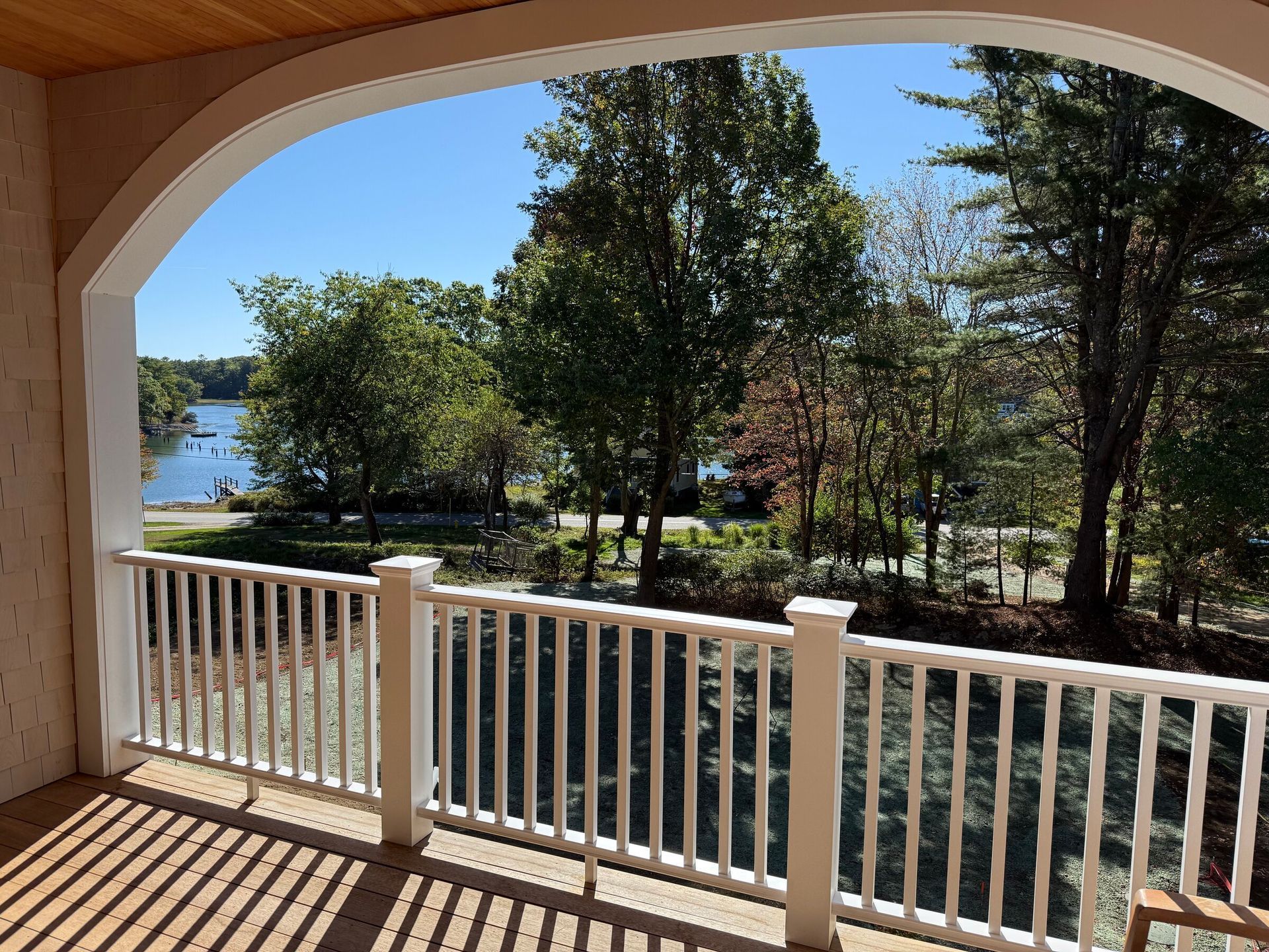 Covered balcony overlooking trees, water, and a bright blue sky in Kittery, ME