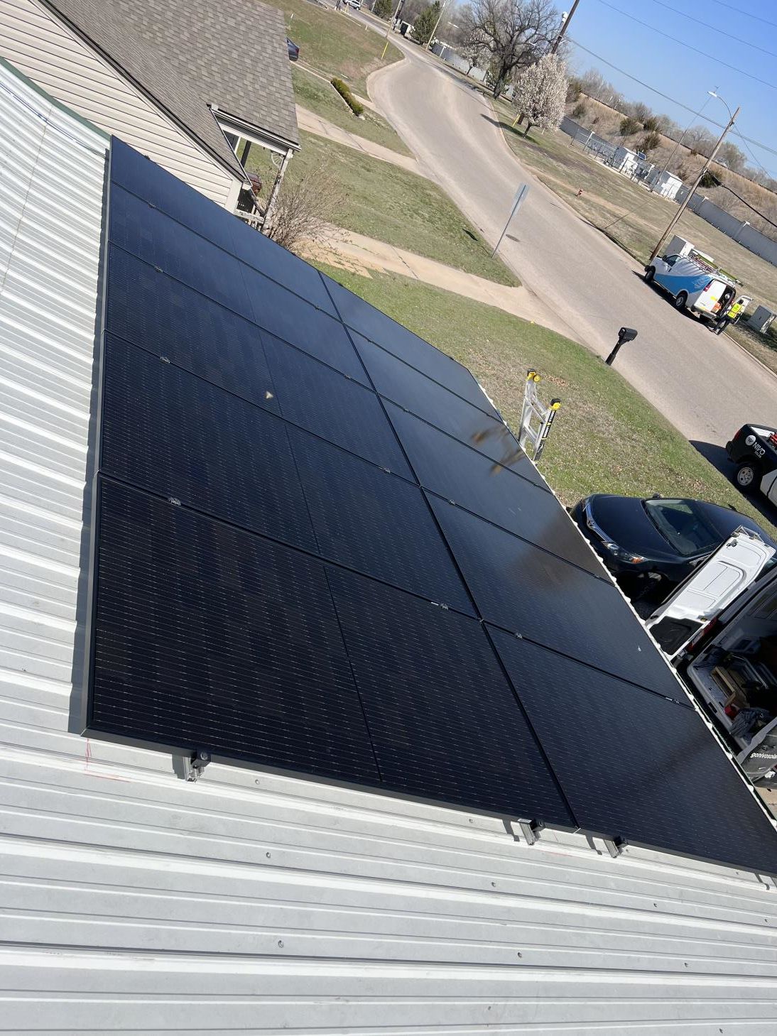 A row of solar panels against a cloudy sky with the sun shining through them.