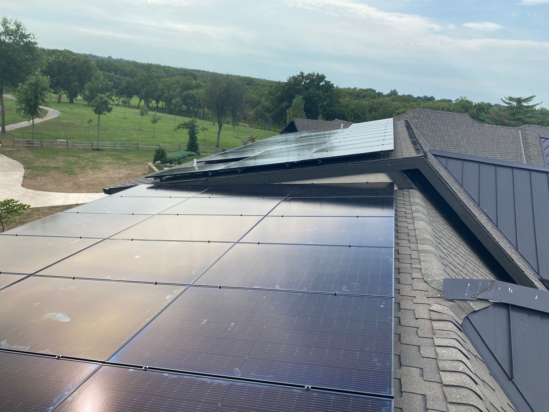 A row of solar panels against a cloudy sky with the sun shining through them.