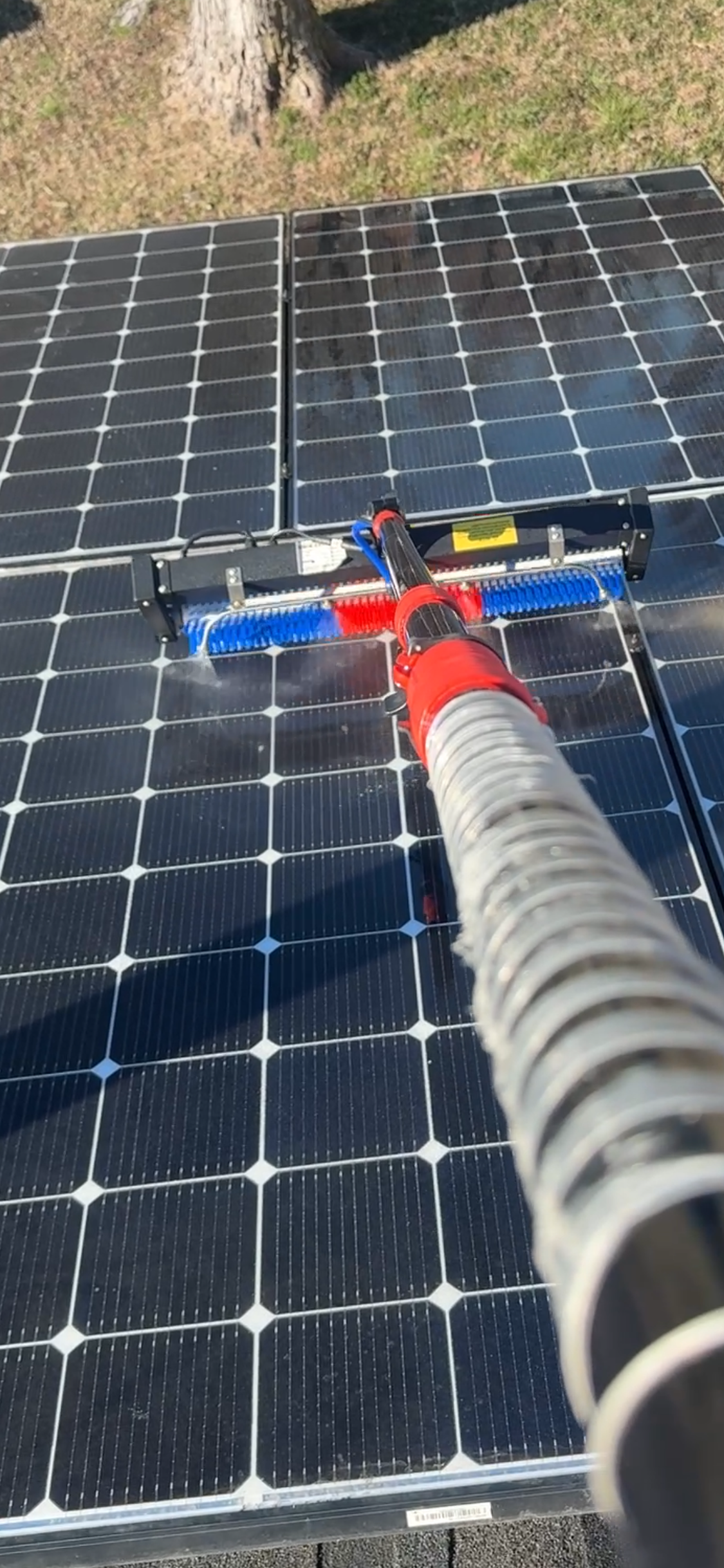A row of solar panels against a cloudy sky with the sun shining through them.
