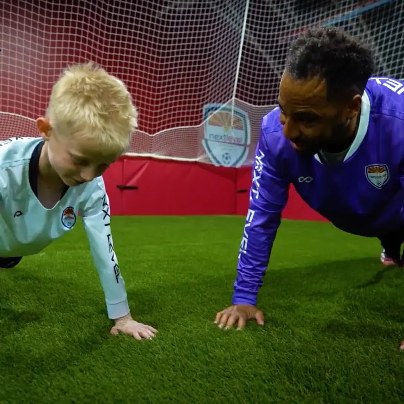 A man and a boy do push ups on a soccer field