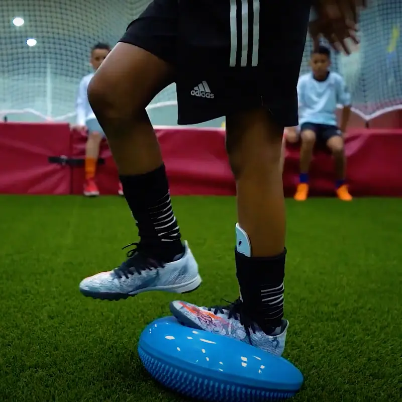 A person wearing adidas shorts is standing on a blue ball