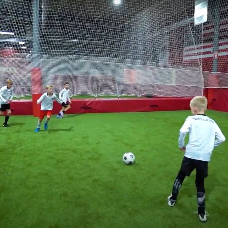 A group of young boys are playing soccer on a indoor field