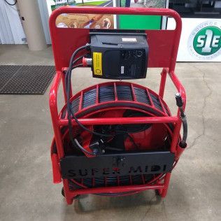 Red cart with a black camera reel, labeled 