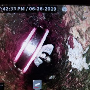 Inside a dark well: a section of pipe, a figure in white clothing.