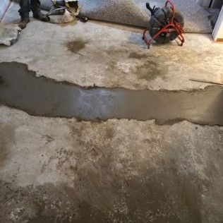 Concrete floor with a trench filled with wet cement; a drain cleaning machine sits nearby.