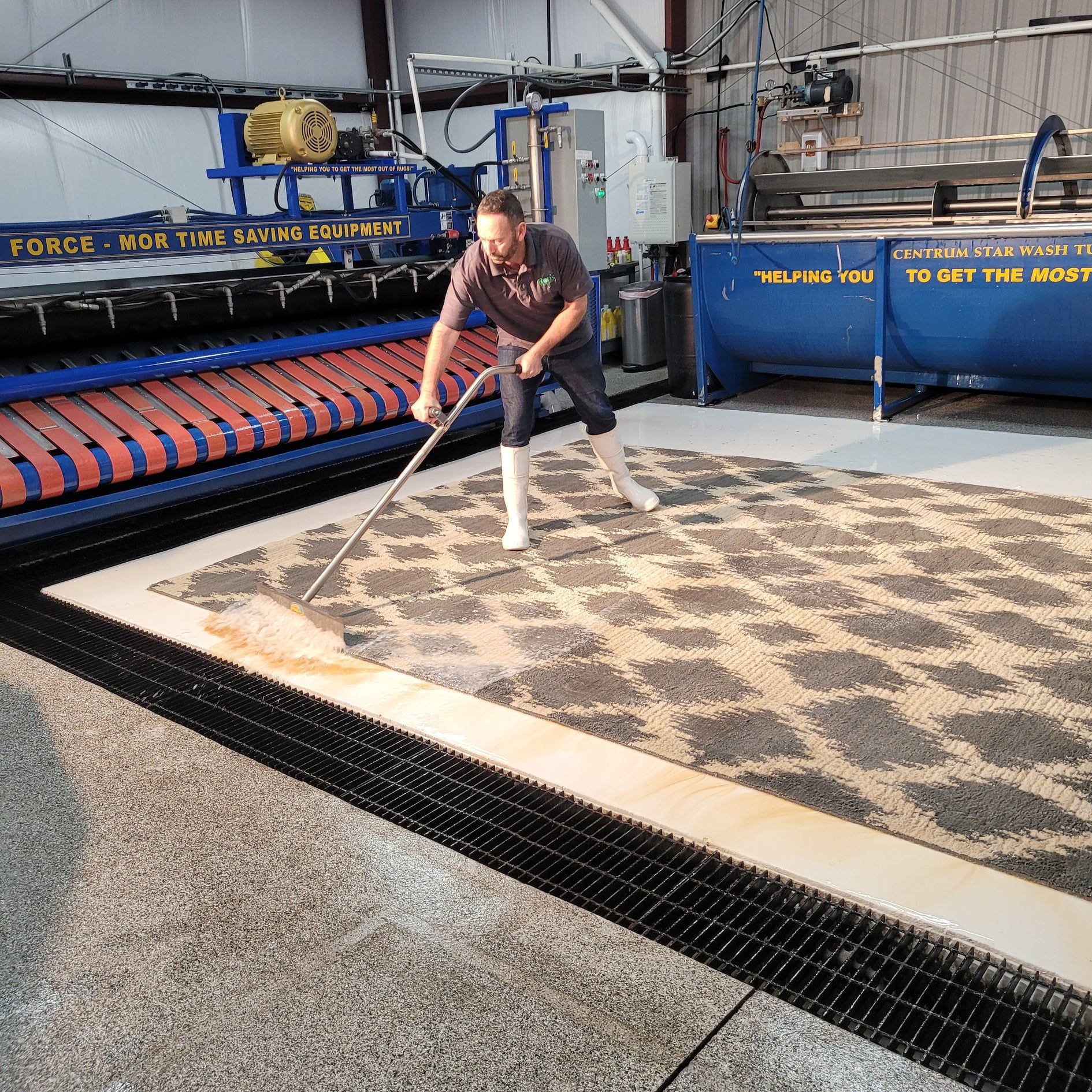 Worker spreading material on a patterned carpet in an industrial textile facility