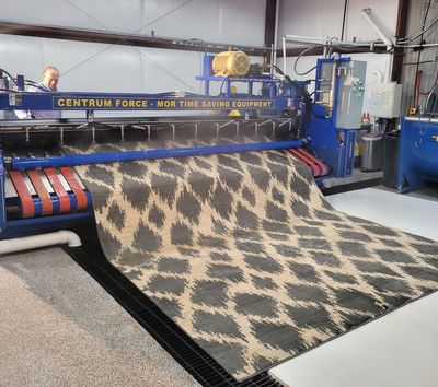Large textile machine feeding a patterned carpet in an industrial factory setting