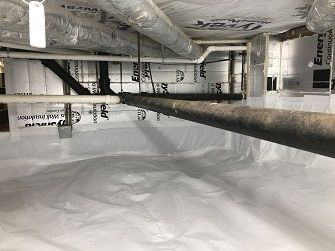 Insulated attic crawlspace with white vapor barrier and exposed ducting and pipes