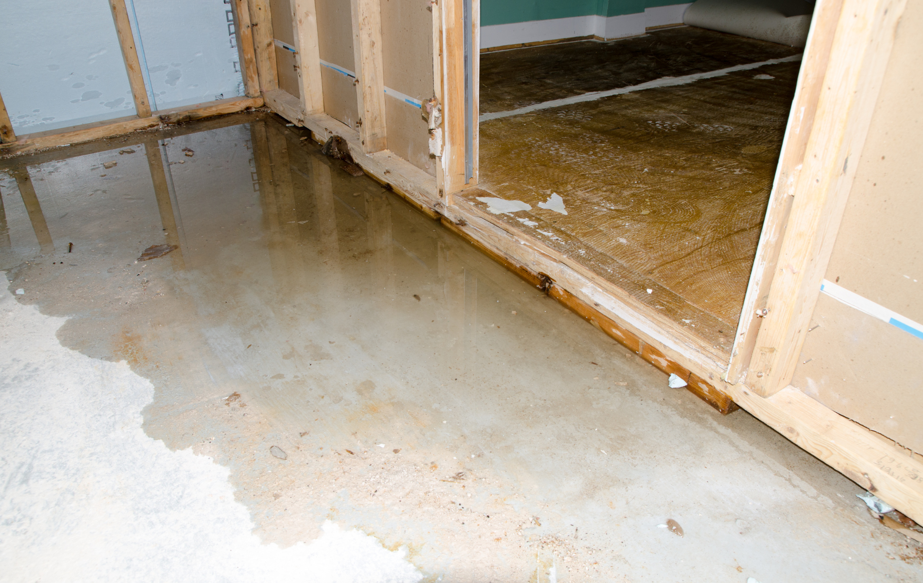 Water-damaged room with wet concrete floor and a flooded doorway opening