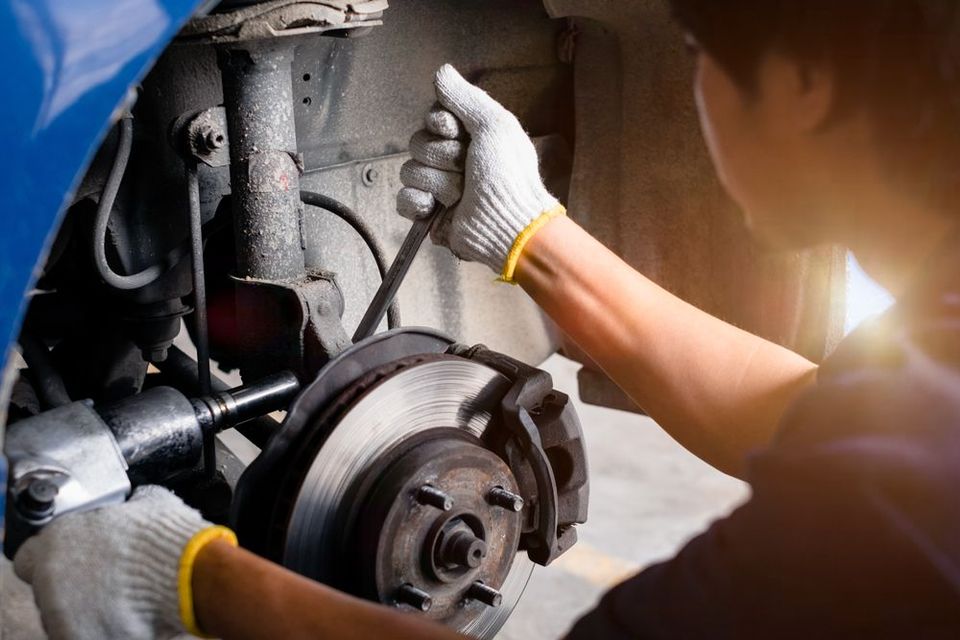 A Mechanic Uses a Tool to Perform Maintenance on A Car Suspension Assembly — Morisset Automotive in Morisset, NSW