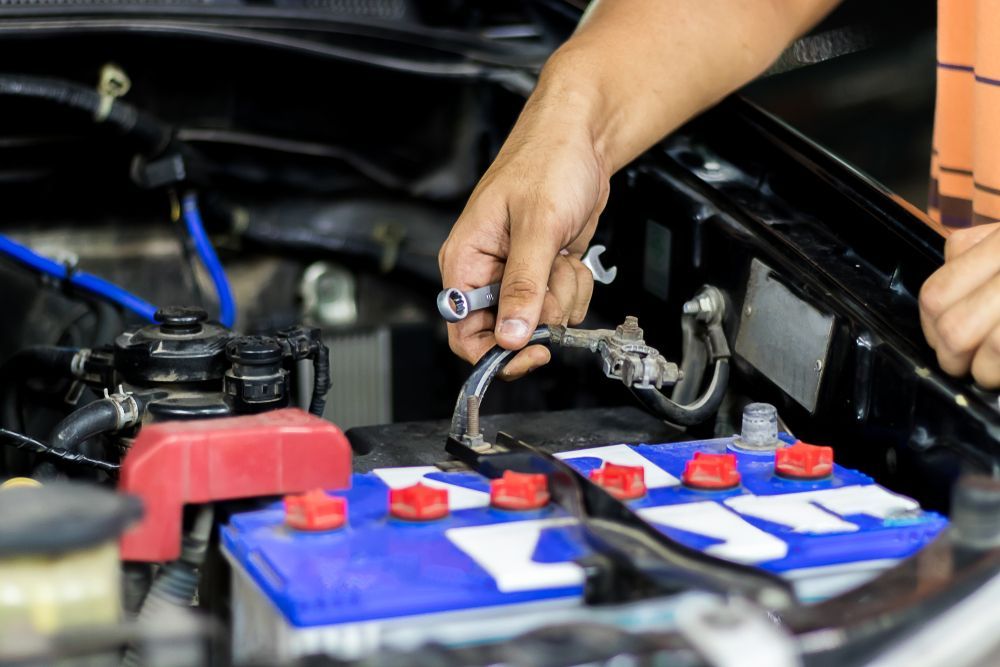 A Person Uses a Small Wrench to Tighten or Loosen a Terminal on A Car Battery — Morisset Automotive in Morisset, NSW