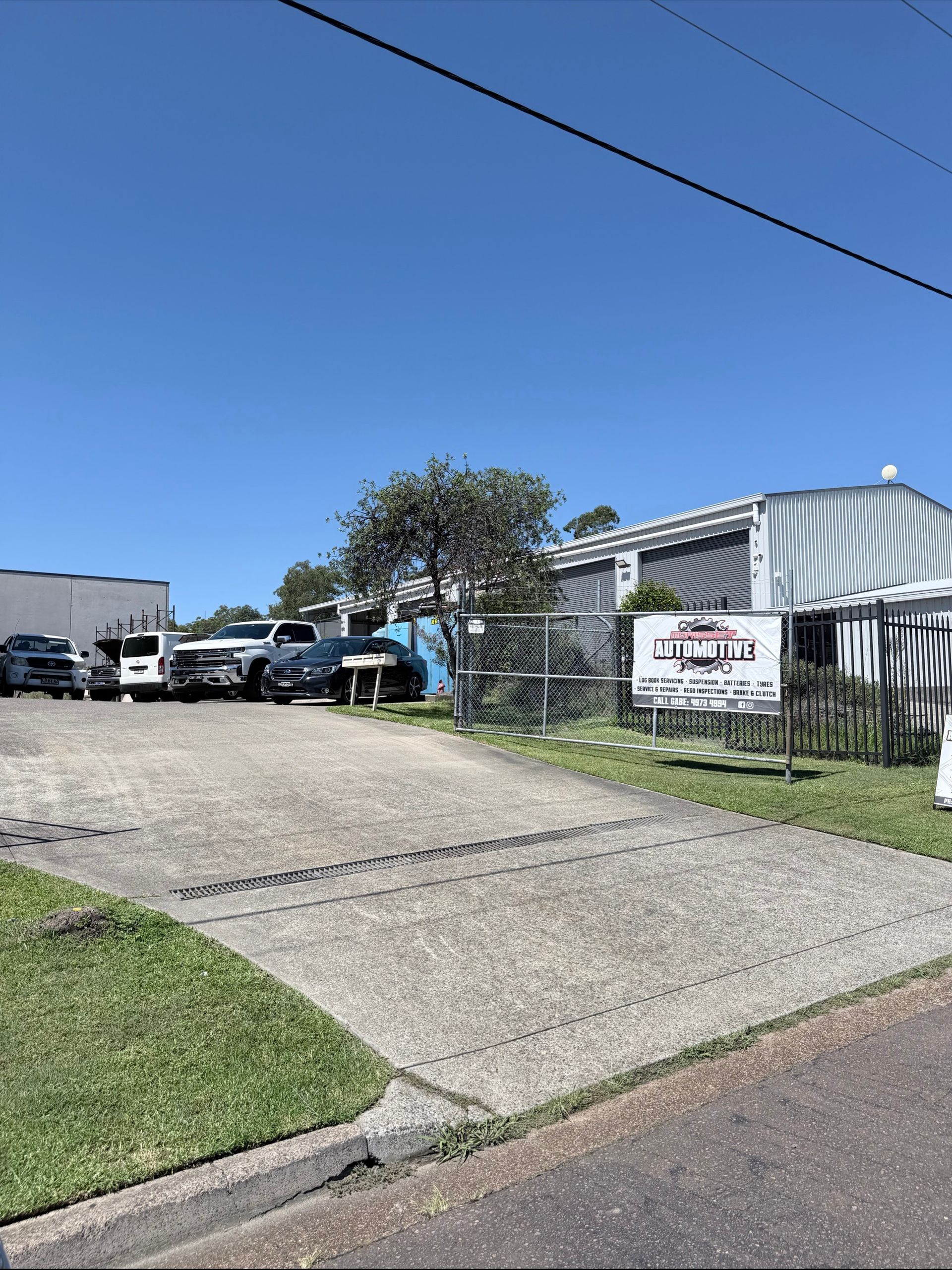 A Driveway Leads to A Property with A Sign in Front of A Corrugated Metal Building — Morisset Automotive in Morisset, NSW