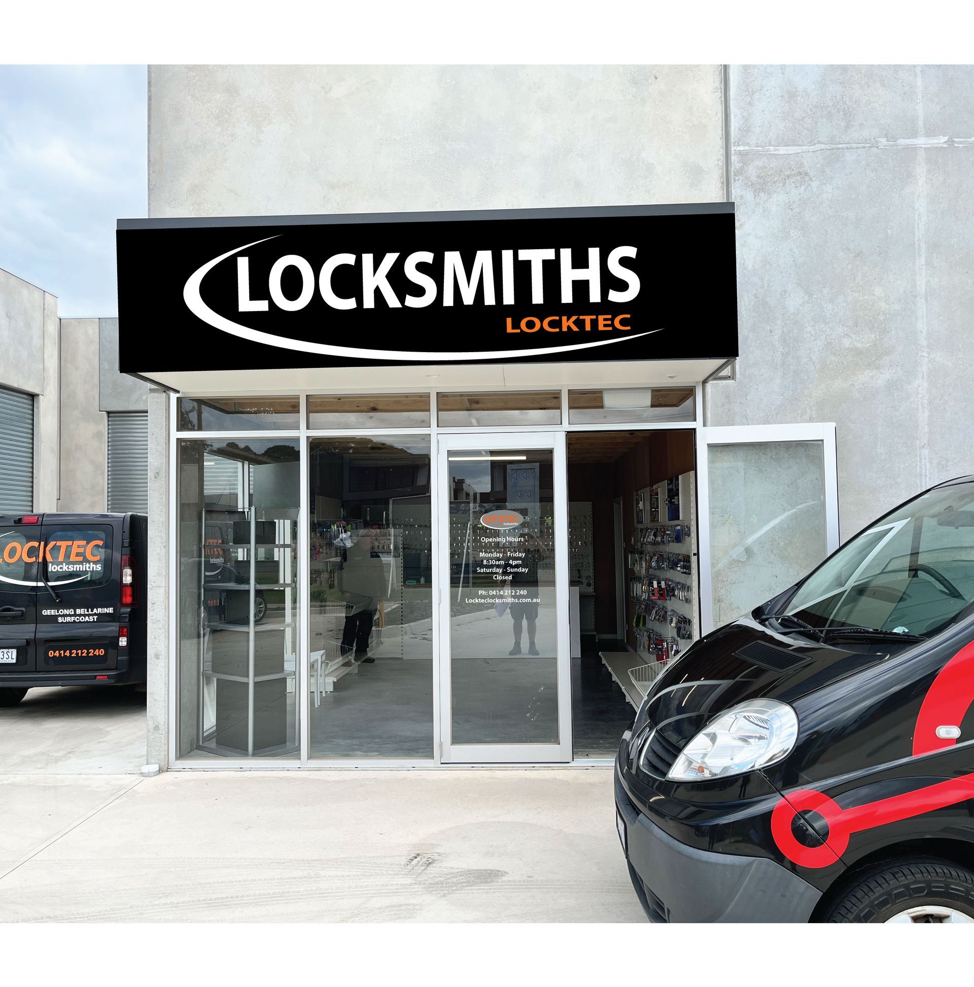 Locksmith shop with black and white sign. A black van with red accents is parked in front of the shop.