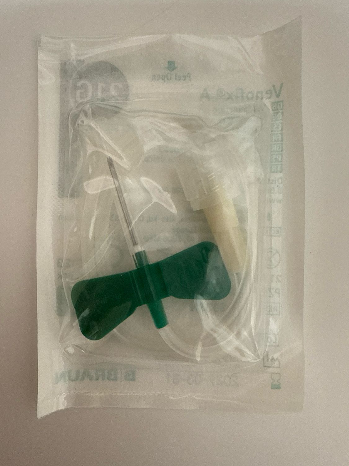 Clear packaged medical needle with green handle on a sterile tray