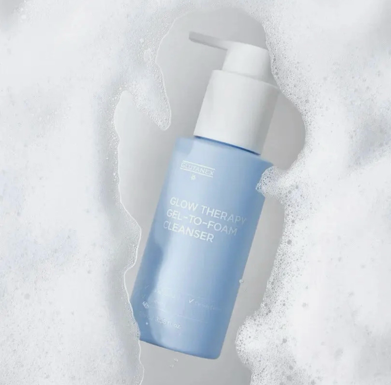 Blue pump bottle of cleanser on a white foamy background