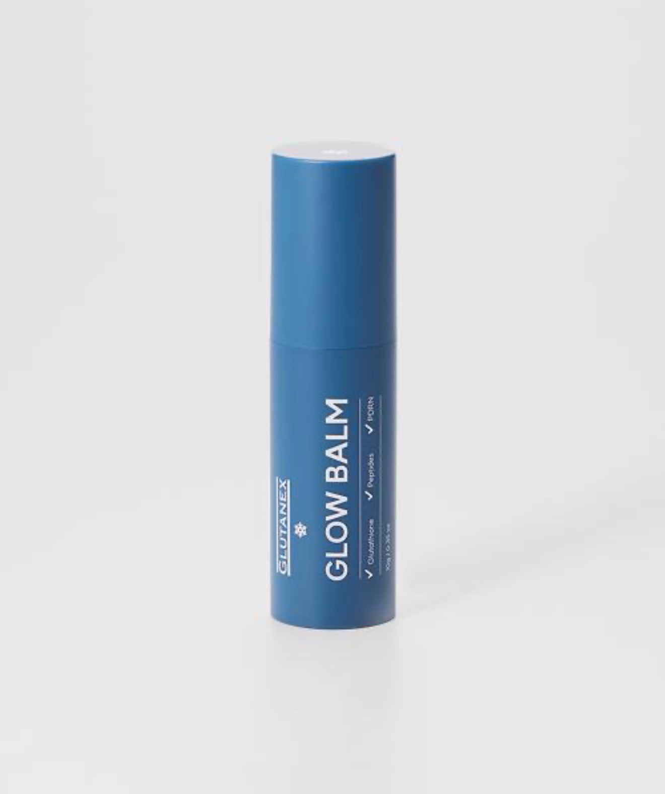 Blue cylindrical Glow Balm tube on a light gray background