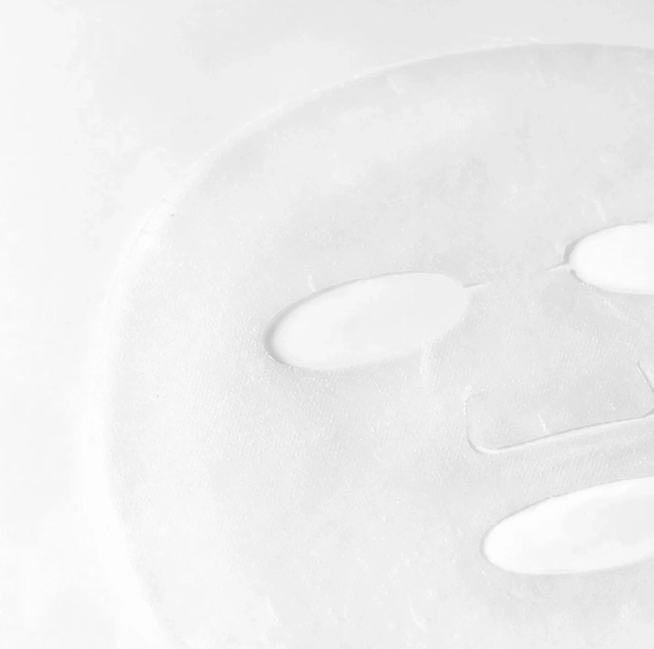 White masquerade-style face mask with eye cutouts and nose, viewed close up