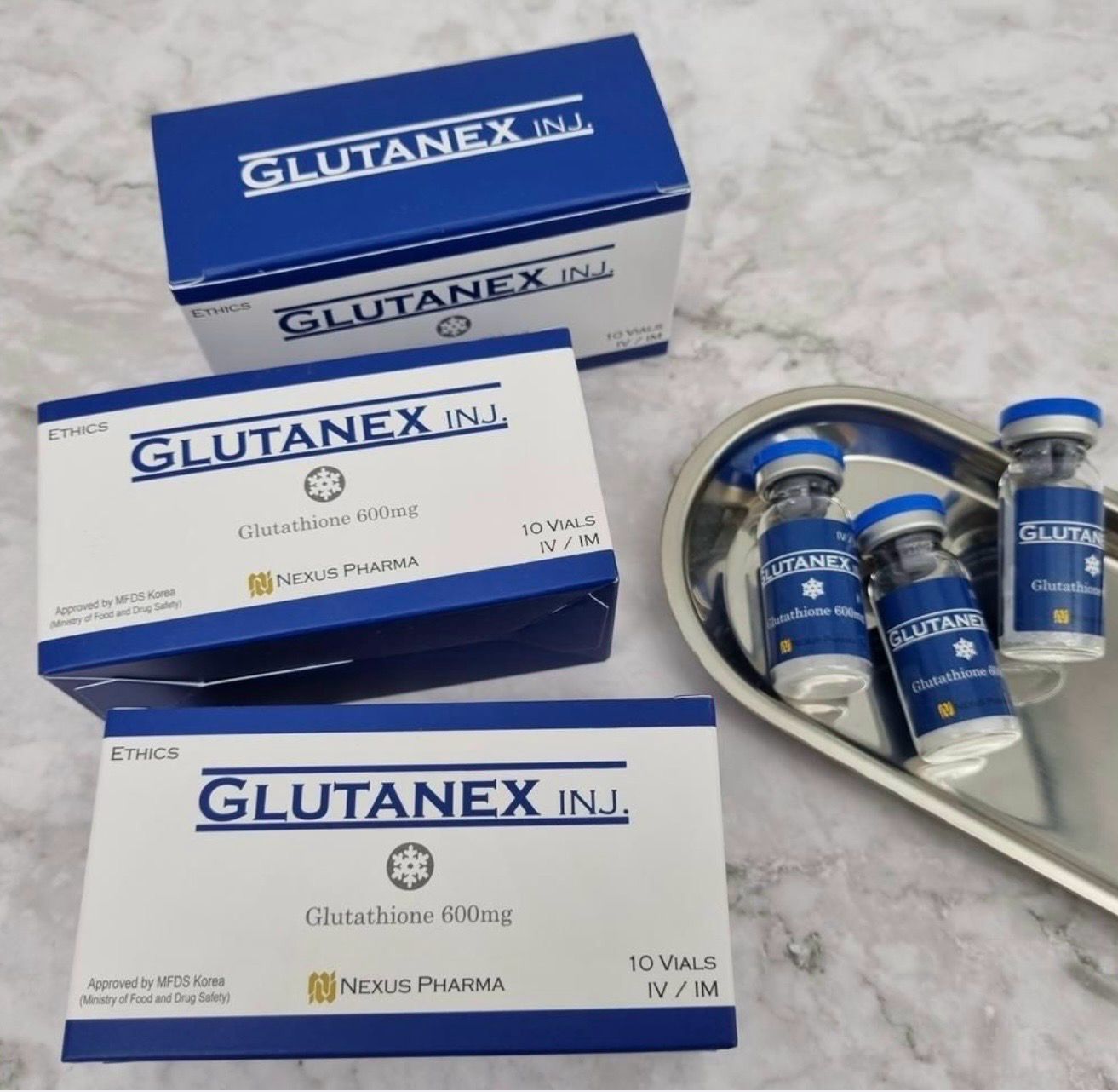 Blue-and-white GLUTANEX IV boxes and vials arranged on a tray and marble surface