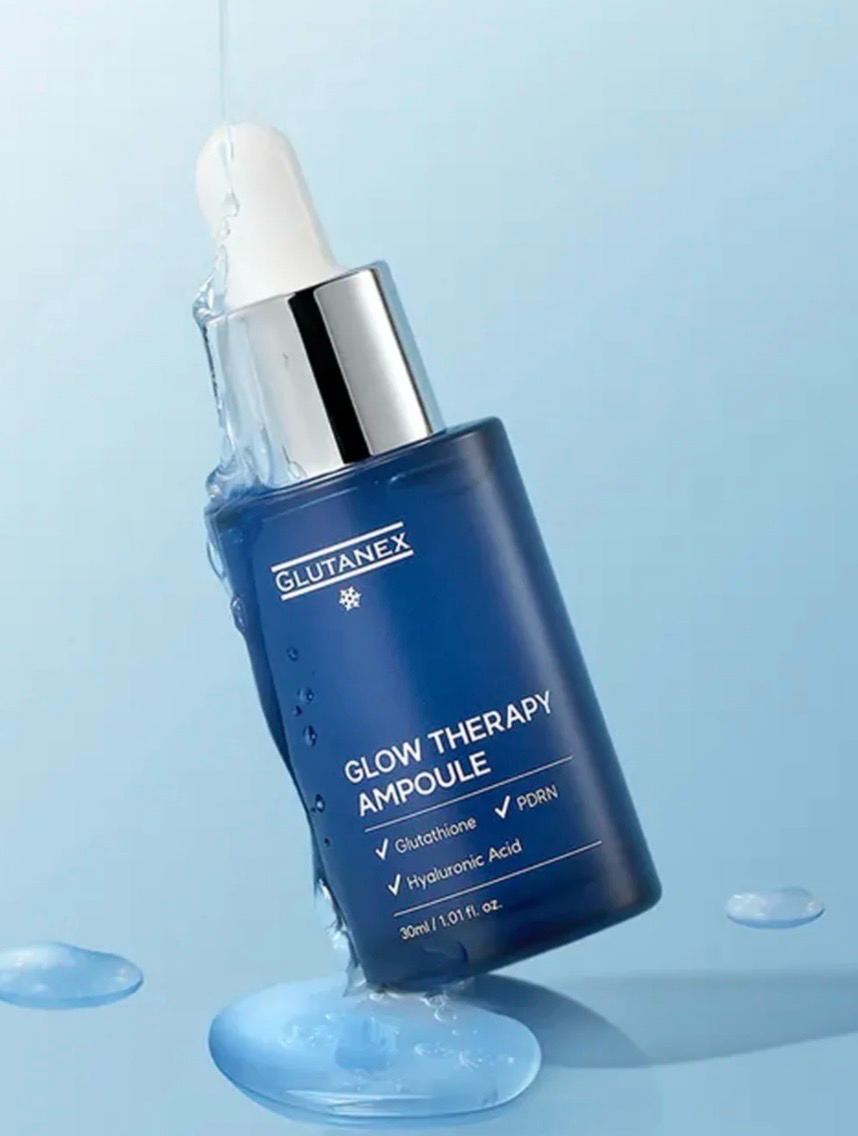 Blue serum dropper bottle on a light blue background, tilted beside glossy droplets