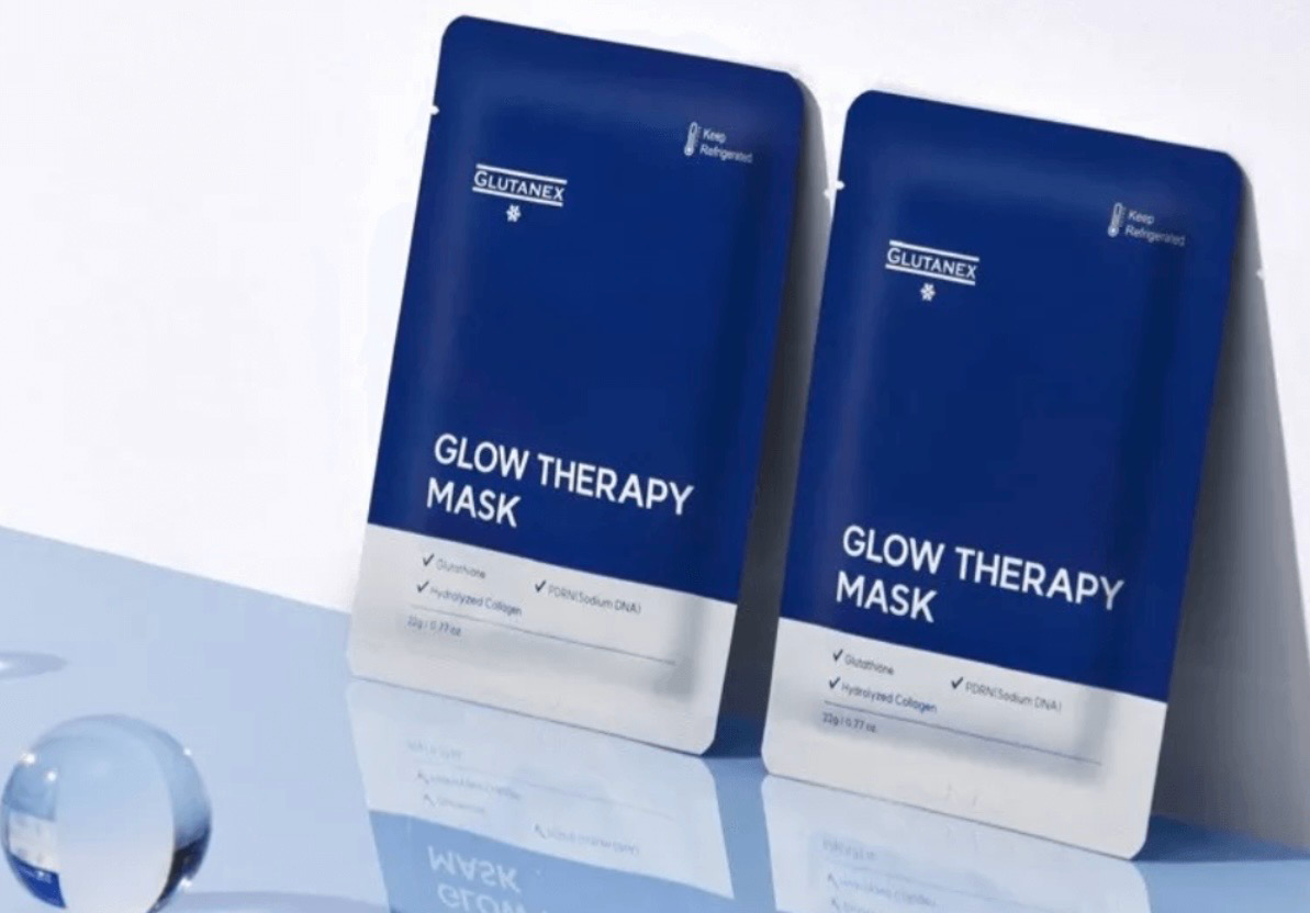 Two blue Glow Therapy Mask packets on a light reflective surface