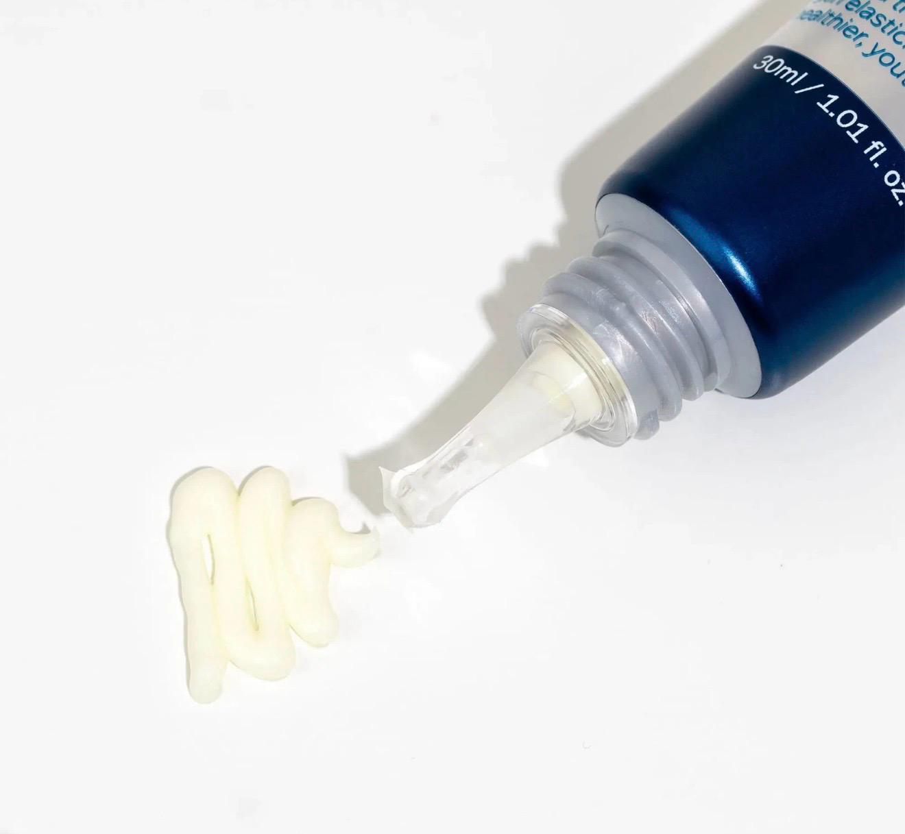 Blue tube squeezing white cream onto a white surface