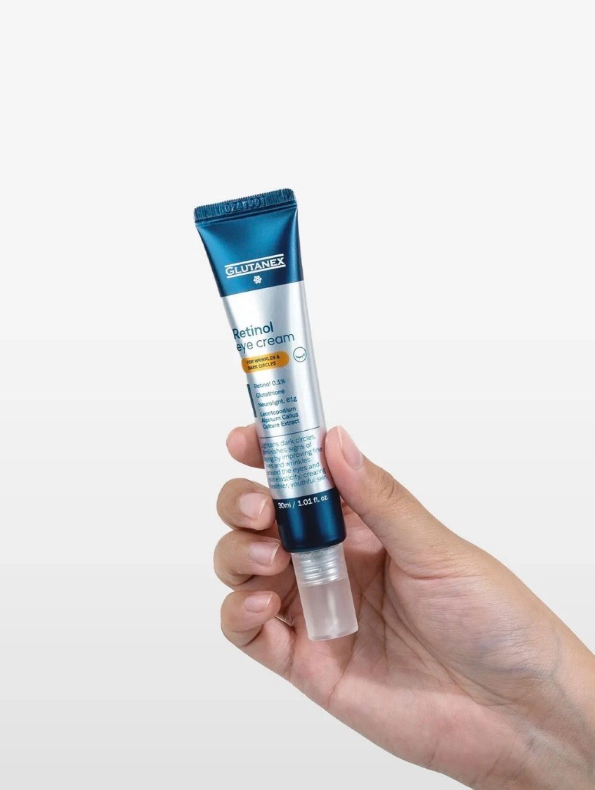 Hand holding a blue-and-white tube of cream against a white background