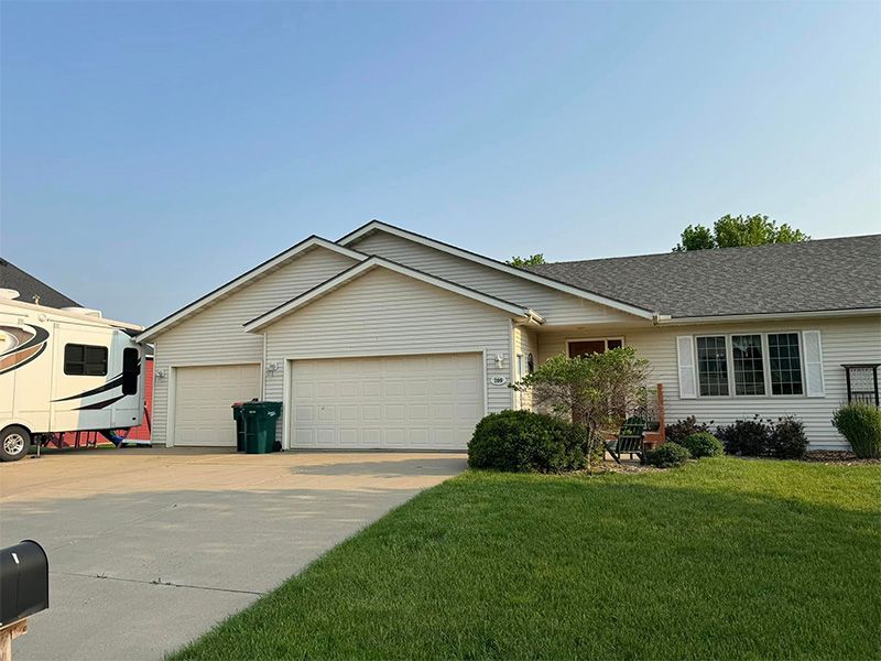 Ranch-style house with three-car garage, driveway, and RV parked beside it on a sunny day.